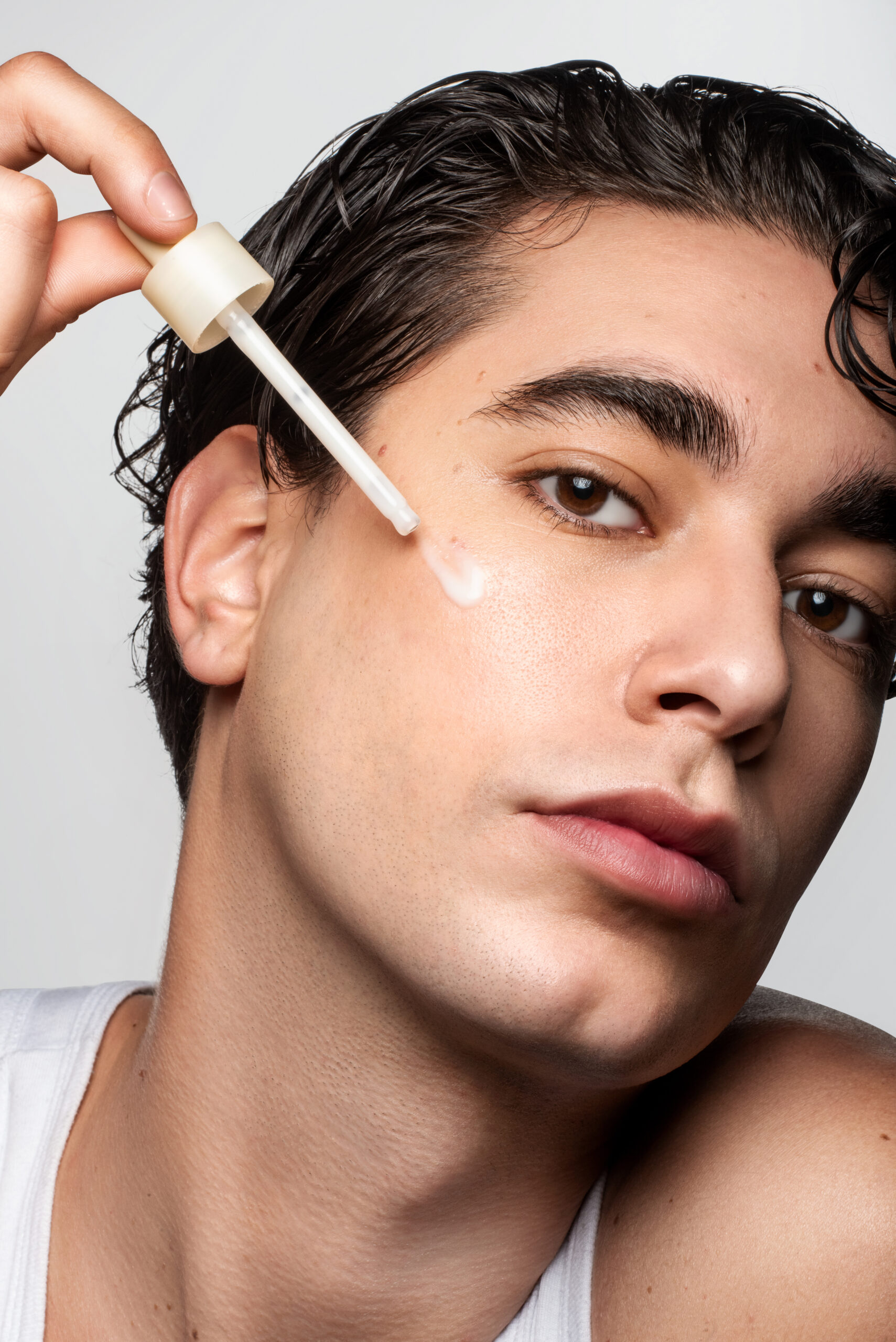Portrait beauté en studio montrant un modèle à la peau naturelle utilisant un sérum skincare, photographie réalisée par Julie Mannina, cofondatrice du Coco Studio.